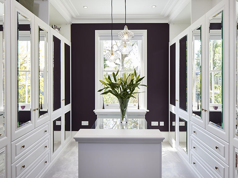 A luxurious dove white fitted dressing room with detailed brass dahlia handles A luxurious dove white fitted dressing room with detailed brass dahlia handles