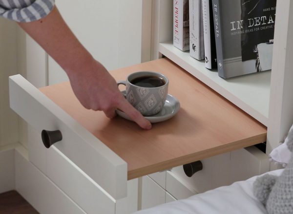 Woman putting down a cup of coffee on a pull out bedside table