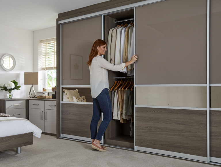 Woman sliding open the door of a floor to ceiling fitted wardrobe